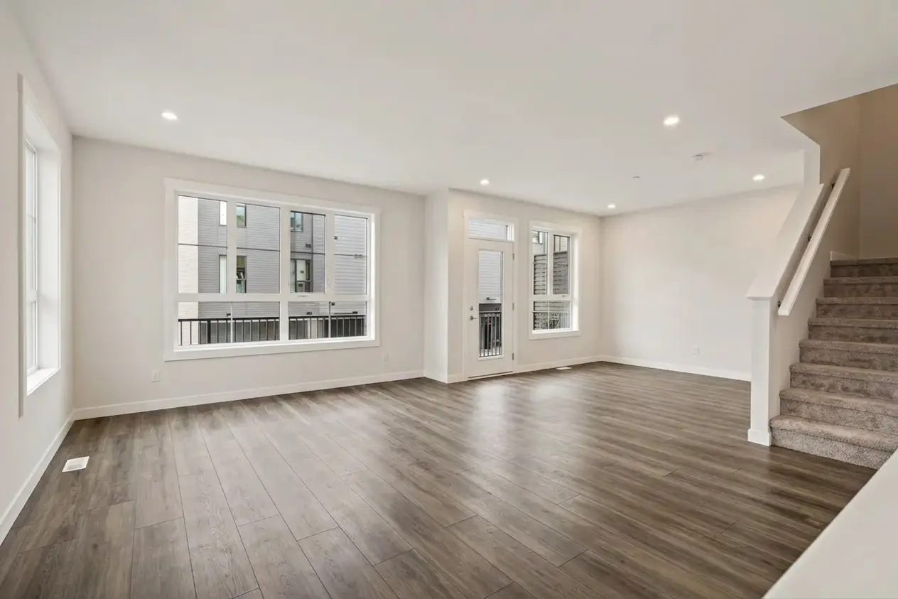 Before staging in an empty Calgary living room with dark wood flooring
